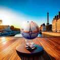 Load image into Gallery viewer, CITY SERIES PARIS GLOBE MOVA displayed outdoors with Eiffel Tower at sunset and Seine reflections.