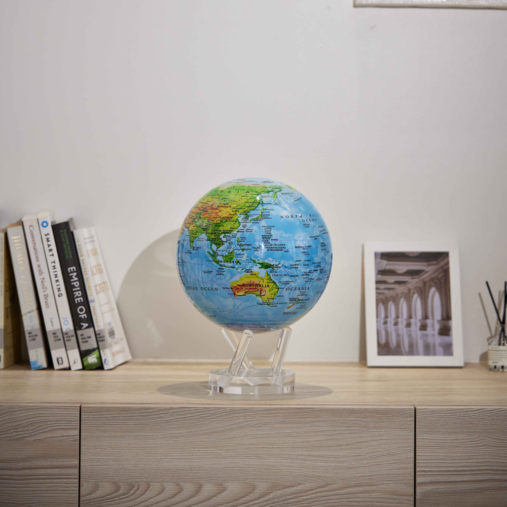 Colorful relief map MOVA Globe displayed with books and framed decor