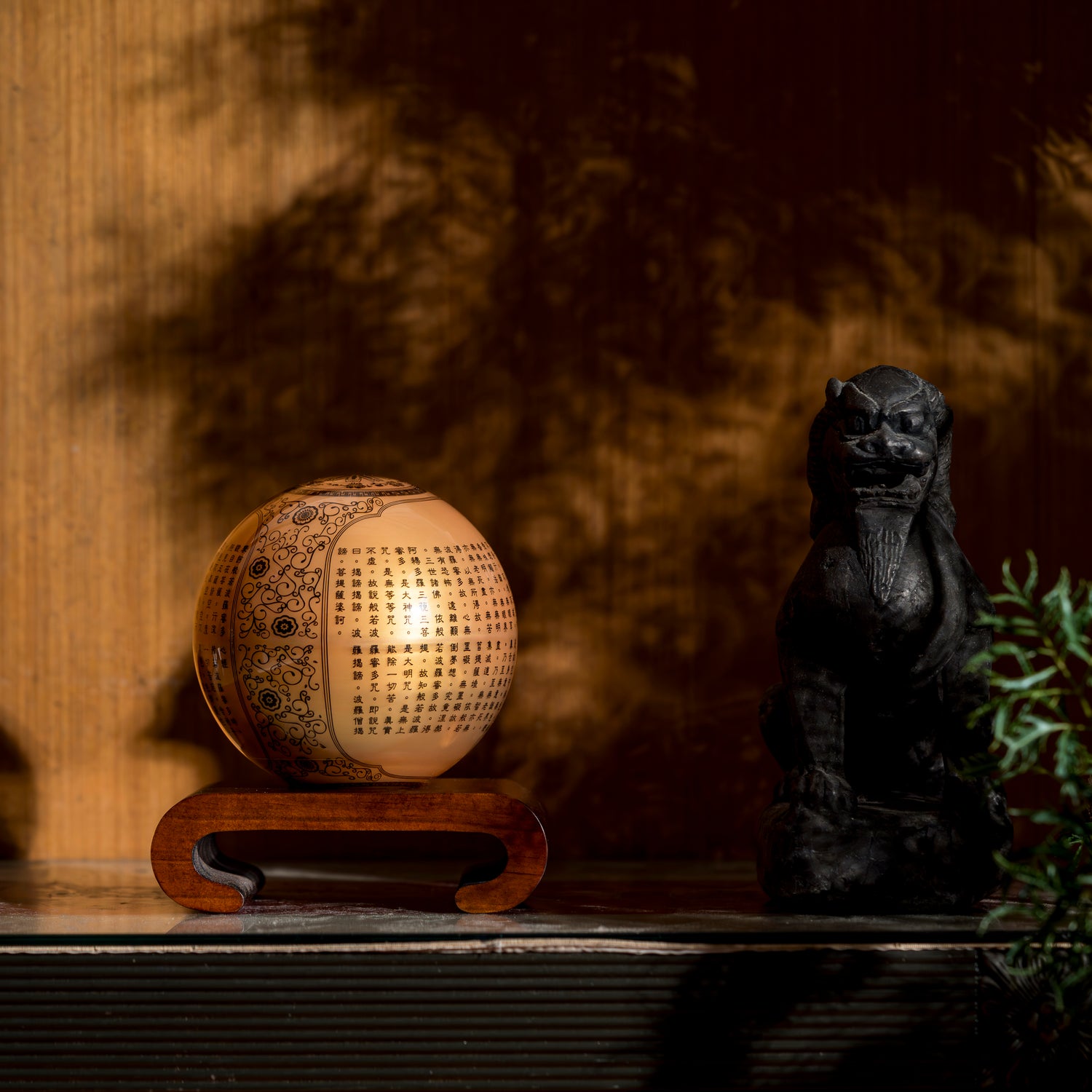 HEART SUTRA GOLD GLOBE glowing warmly on wood base, refined centerpiece blending spiritual symbolism with contemporary elegance.