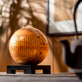 Illuminated HEART SUTRA GOLD GLOBE with inscriptions, displayed on square stand, a unique fusion of tradition and kinetic art.