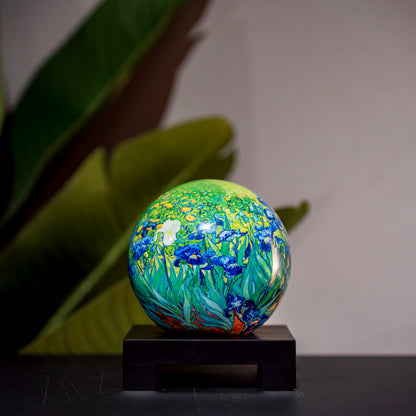 Van Gogh Irises MOVA Globe, displayed with greenery background, sophisticated rotating art piece for stylish home décor.