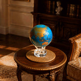 Cerulean Blue & Gold MOVA Globe displayed atop a classic wooden side table in an elegant library interior.