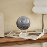 Moon MOVA Globe on console table beside magazines and lamp