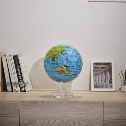 Colorful relief map MOVA Globe displayed with books and framed decor