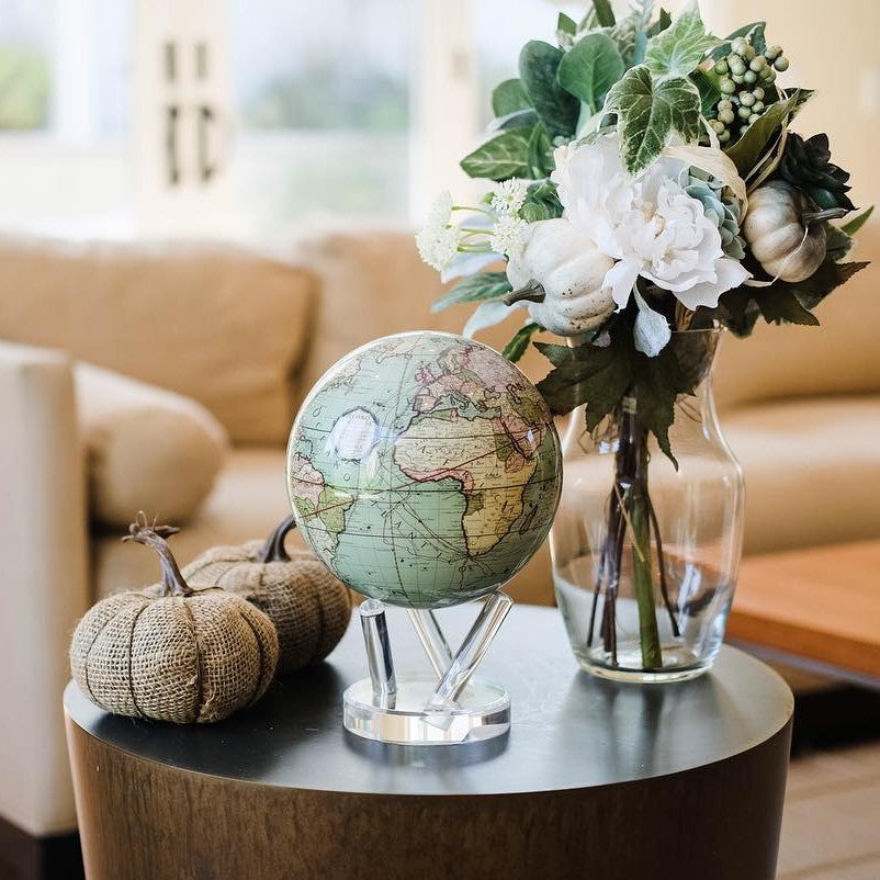 Seafoam green MOVA Globe displayed with flowers in a living room