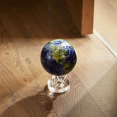 Earth MOVA Globe illuminated by sunlight on a warm wood flooracrylic base